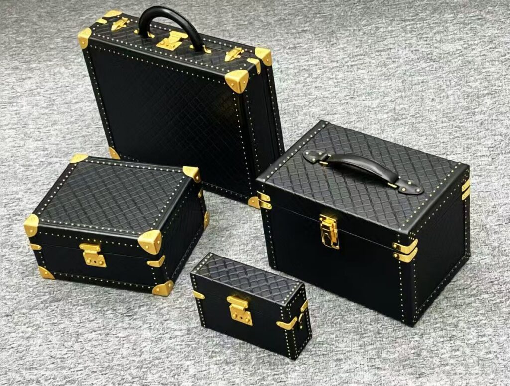 Black croc-embossed hard case set with gold trunk hardware - corner protectors, clasps and handles by Maya Metal