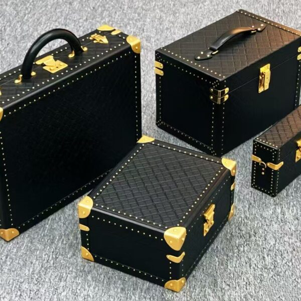 Modern black and gold hard trunk cases with brass corners, latches and nailhead stud trim